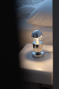 A modern bedroom featuring metallic table lamp with a bulb design.