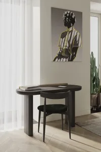 A stylish minimalist desk setup featuring a wooden desk and chair in a contemporary room with a large window and a cactus pla