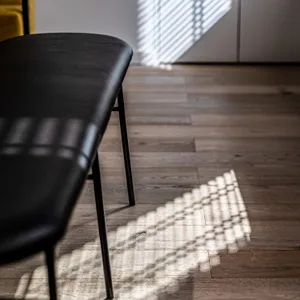 A modern interior space featuring a wooden floor with patterns created by light filtering through a window.