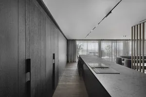 Modern kitchen featuring dark wood cabinets, a sleek countertop, and large windows with sheer curtains.