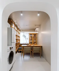 A modern kitchen area with a dining table and chairs, a bookshelf, and a laundry area featuring a washing machine and dryer.