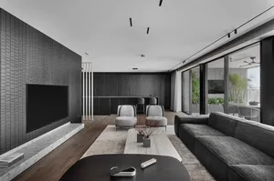 A modern living room with a concrete wall, a large dark grey sofa, and a minimalist coffee table with decorative items.