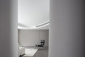 A modern living room featuring minimalist furniture and a concrete floor.