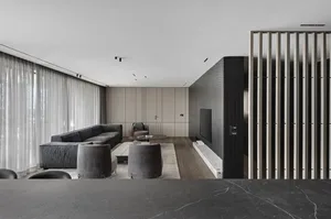 A modern, minimalist living room with dark wood flooring, light-colored walls, and mixed materials including leather furnitur