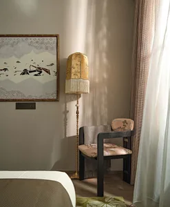 Modern living room showcasing a comfortable chair with patterned cloth upholstery and a decorative floor lamp with a floral-p