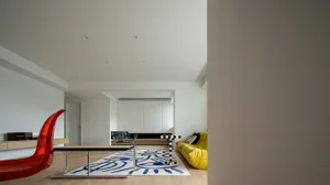 Modern living room featuring a contemporary wooden floor, glass windows, and upholstered furniture with a colorful rug.