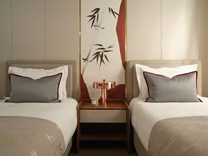 Modern minimalist bedroom with fabric bedding, wood headboards, and a metal desk lamp.