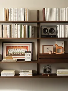 A modern, well-organized bookshelf filled with books, a wooden rocking horse, and a speaker.