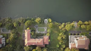A modern residential property with a brick roof overlooking a large body of water.