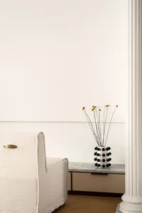 A minimalist modern interior with white marble accents and a white sofa against a white wall.