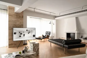 Modern living room with wooden and leather furniture, a marble coffee table with a green apple, and a large screen displaying