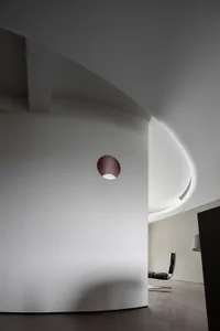 Modern, minimalist room with a sleek, curved concrete wall and a single steel frame chair.