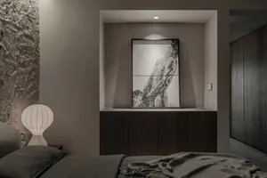 A modern, minimalist bedroom with dark wood furniture, gray bedding, and a textured wall.