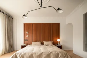 A minimalist bedroom with a wooden headboard and beige bedding.