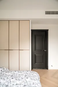 Sparsely furnished, minimalist bedroom featuring a bed with floral bedding and wooden flooring.