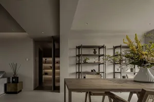 A minimalist dining room featuring wooden furniture and shelves with decorative items.