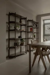 A minimalist dining room featuring wood shelves with various decorative items and a wooden dining table.