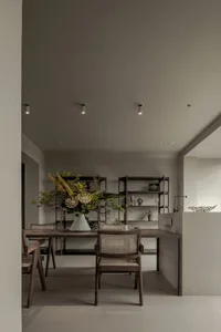 A modern, minimalist home office featuring wood furniture and a vase with floral arrangement.