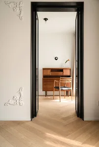 A minimalist residential interior featuring wooden floors and a combination of modern and mid-century design elements.