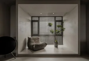 Modern minimalist window seat with a textured concrete finish and textured cushion, featuring a sleek black circular wood cha