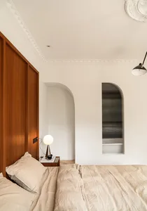 A bed with beige linens and a wooden headboard in a modern bedroom setting.