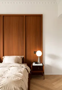 A modern minimalist bedroom featuring a wooden headboard and floor-to-ceiling wooden paneling.
