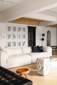 Modern minimalist living room featuring a white leather sofa, marble side table, and wooden flooring.