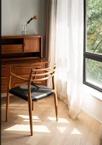 A modern office space featuring a wooden and cloth booth with a glass vase containing a flower on top, natural light streamin