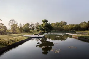 A serene water feature with concrete edges surrounded by grass and trees, reflecting the surrounding environment.