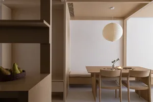 A minimalist dining room featuring wooden furniture and a round paper lantern pendant light.