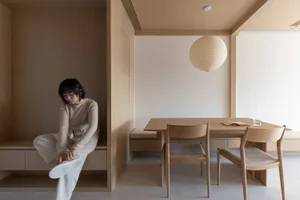 A minimalist dining area featuring wooden furniture and a hanging paper lantern.