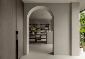 Minimalist living room with concrete walls and floor, featuring natural elements and a single decorative object.