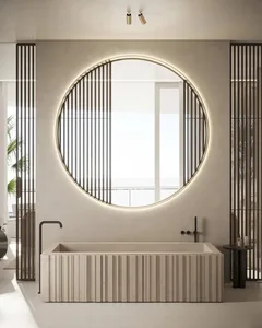 A modern bathroom interior featuring a white marble bathtub and a large round mirror with backlighting.