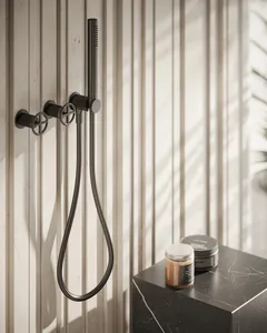 Black metallic bathroom faucet and showerhead system mounted on a white wooden panel wall.