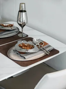 A modern dining setting featuring metallic tableware and glassware on a marble table.