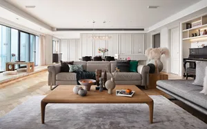 A modern living room featuring a wooden coffee table, a leather sofa adorned with various textured pillows, and a textured ru