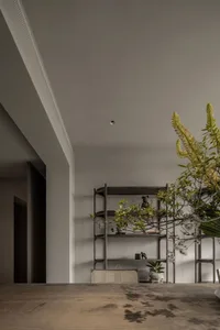 A modern minimalist living room with wooden flooring, metal shelving, and potted plants.