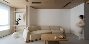 A modern living room with a neutral color palette, featuring a beige sofa, a wooden coffee table, and a minimalist design.