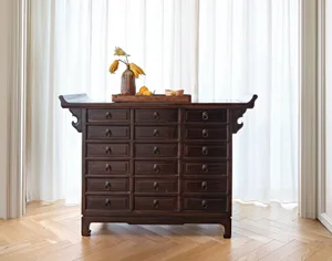 Dark wooden cabinet with numerous drawers and a vase with dried flowers and fruits on top.