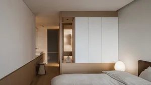 Minimalist bedroom with wooden accents, white walls, and a simple furniture layout.