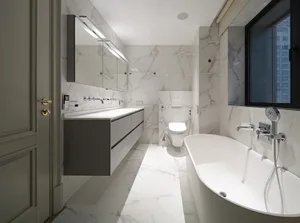 Modern bathroom with marble walls, floor, and countertop featuring a freestanding tub, vanity, and toilet.
