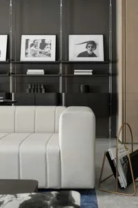 A modern industrial living room with a white leather couch, black shelves, and black and white wall art.
