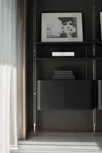 A modern black metal shelf with books and a framed black and white portrait of a woman.