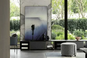 A modern living room featuring marble walls and furniture, with a large abstract art piece and a large window overlooking a g