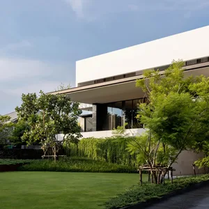 A modern residential building with a white exterior and a large overhanging roof.