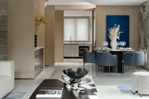 A modern residential dining space featuring a contemporary table with blue chairs, a marble coffee table, and a blue abstract