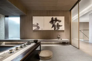 A modern tea room featuring a wooden floor, concrete walls, and glass elements