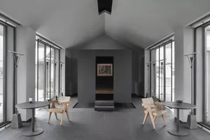 Modern industrial waiting area with concrete walls, wooden furniture, and vertical windows