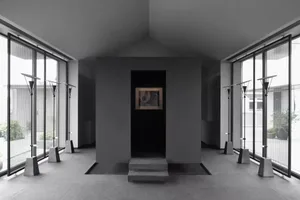 A minimalist art gallery showcases art pieces framed by concrete walls and large glass windows.