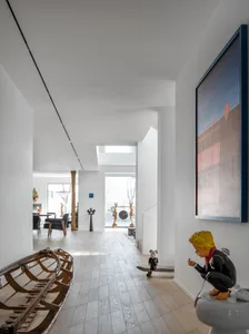 A modern living room featuring a white color scheme, wooden floors, and glass elements.